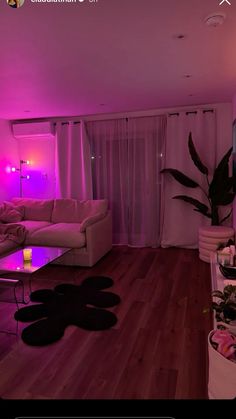 a living room filled with furniture and pink lighting on the walls, along with a coffee table