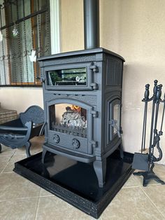 an old fashioned stove sitting on top of a tile floor next to a chair and fireplace