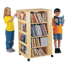 two children standing next to each other in front of a book shelf filled with books