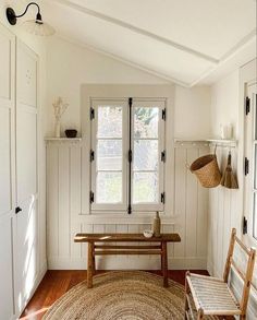 a room with white walls and wood flooring has a bench in front of the window