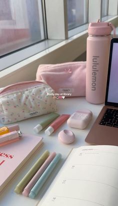 an open laptop computer sitting on top of a white table next to a pink bag