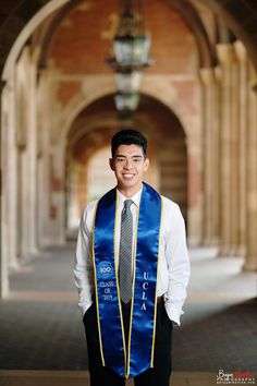 a man wearing a blue vest and tie standing in front of an archway with columns