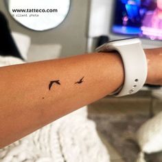 a woman's arm with a small bird tattoo on the left side of her arm