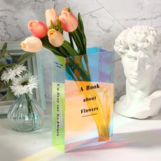 a book about flowers sits next to a vase with tulips