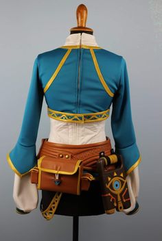 a woman's blue and yellow outfit with an eye patch on the chest, holding a brown purse