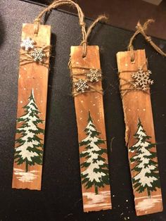 three wooden tags decorated with christmas trees and snowflakes are hanging from twine