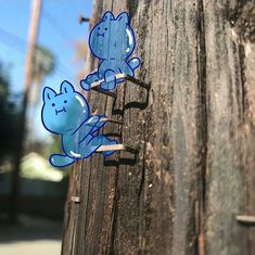 two stickers on the side of a telephone pole that has been painted with blue cats