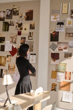 a woman standing in front of a wall covered with pictures and papered notes on it