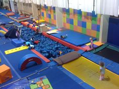 children playing in an indoor trampoline park with slides and play mats on the floor