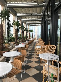 tables and chairs are lined up on the checkered floor in an indoor restaurant with palm trees