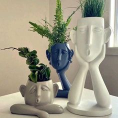 three vases with plants in them sitting on a table next to a planter