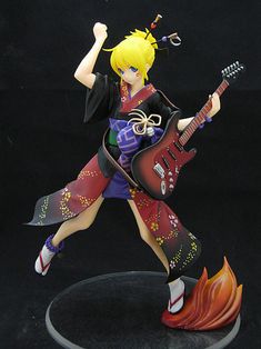 a figurine is posed on a black background with an electric guitar in the foreground