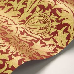 a red and gold wallpaper with an intricate design on it's back side