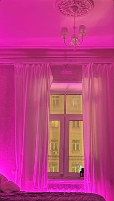 a bedroom with pink lighting and curtains