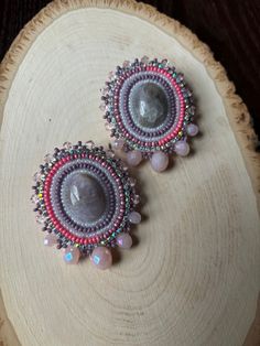 two pairs of beaded earrings sitting on top of a piece of wood