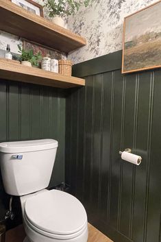 a white toilet sitting inside of a bathroom next to a wooden shelf filled with items