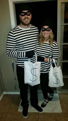 a man and woman dressed up as batman and catwoman, standing in front of an open door