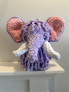 an elephant stuffed animal sitting on top of a white shelf