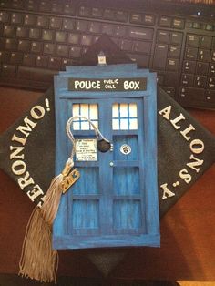 a blue phone booth sitting on top of a wooden desk next to a keyboard and mouse