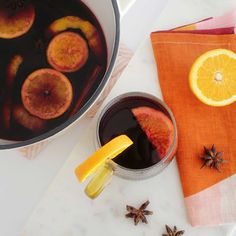 a pot filled with liquid next to an orange slice and star anise