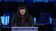 a woman standing at a podium in front of microphones