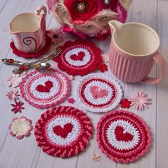 pink and white crocheted coasters with hearts on them next to coffee cup