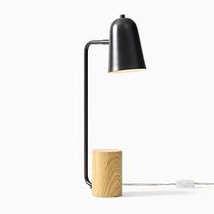 a lamp that is on top of a wooden block with a black shade over it