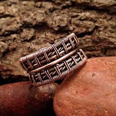 two rings sitting on top of rocks next to each other, one is made out of copper