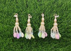 three pairs of earrings with pearls and feathers on them sitting in the middle of some grass