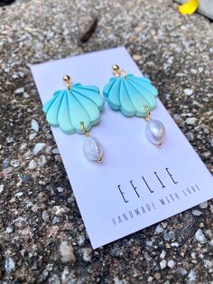 a pair of blue and green earrings sitting on top of a rock