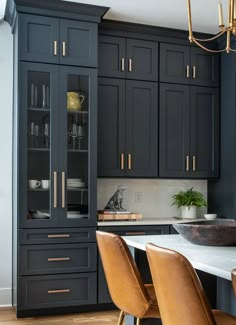 a kitchen with black cabinets and wooden chairs