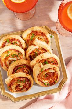 several pastries on a plate next to glasses of wine and an orange slice in the background