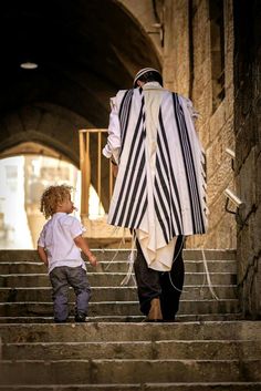 a little boy standing next to a man in a priest's robe on some steps