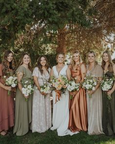 a group of women standing next to each other holding bouquets in front of trees