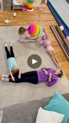 three children laying on the floor playing with an inflatable ball while another child watches