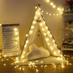 a teepee tent with fairy lights on the floor