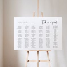 a wooden easel with a seating chart on it in front of a white wall