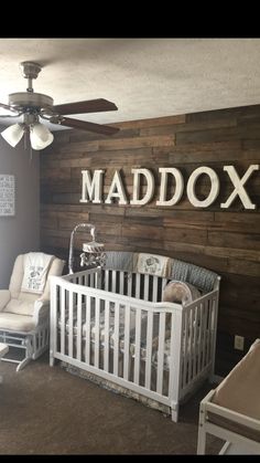 a baby's room with a white crib and wooden name sign above the crib