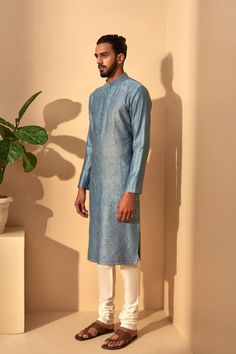 Editor's Note This set features a mineral blue color kurta with metal embroidery paired with cream churidar. Color: Mineral Blue Fabric: Cotton; Silk Chanderi; Terricotton Care: Dry Clean Only About the Designer The Dhruv Vaish Label is a menswear label specializing in Indian and Western Wear, with an exhaustive portfolio of Bespoke Tailoring. Kurta Designs Men's, Metal Embroidery, Indian Groom Wear, Gents Kurta Design, Gents Kurta, Kurta Set For Men, 30 Outfits, Cream Pants, White Kurta