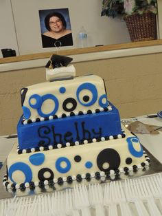 two tiered cake with blue and black designs on it sitting on top of a table