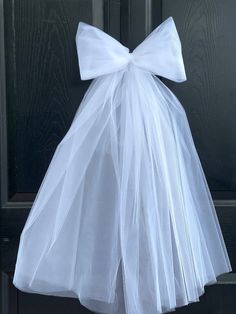 a white dress hanging on a door with a big bow at the top and bottom