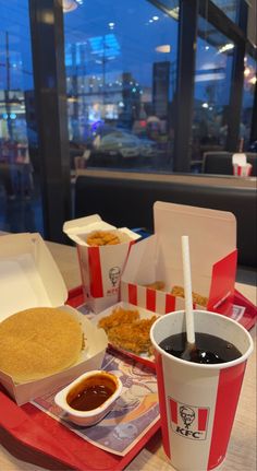 a tray with some food on it and two drinks in front of the trays