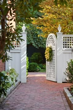 a brick path leads to an open white gate