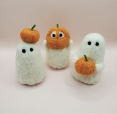 three small white stuffed animals with pumpkins on them