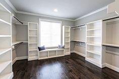 an empty walk in closet with white shelving and wood flooring on the side