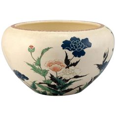 a white bowl with blue and pink flowers painted on the side, sitting in front of a white background