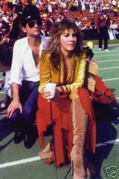 a woman sitting on top of a tennis court next to a man holding a racquet