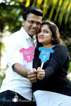 a man and woman pose for a photo holding paper signs with question marks on them