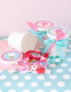 a table topped with lots of cupcakes next to a candy box and lollipop