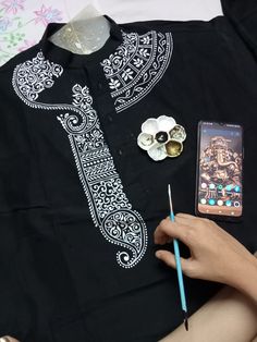 a person holding a cell phone next to a black shirt with white designs on it